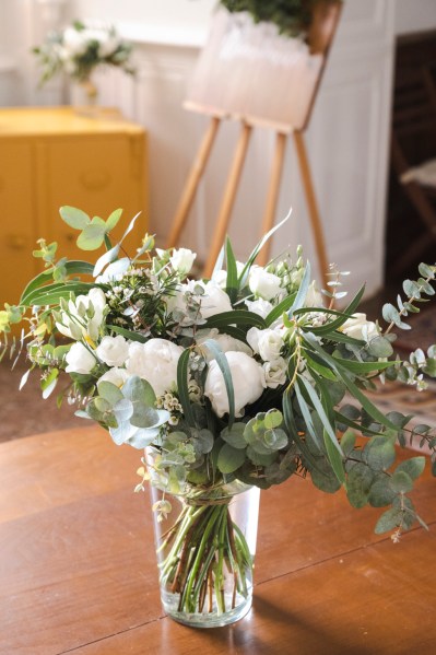 Easel in background close up of white flower roses in vase on table